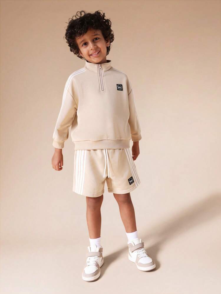 Komplet składający się z bluzy z kapturem i spodenek z suwakiem i detalami w paski