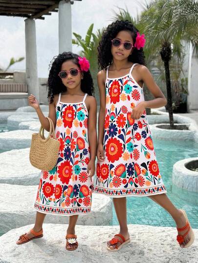Đầm chữ A hai dây in hoa mùa hè cho bé gái, màu kem chủ đạo với họa tiết hoa rực rỡ, dây đeo mảnh, dáng suông thướt tha, thiết kế hoa văn dân gian Bohemian, chất liệu nhẹ, thích hợp cho mùa hè đi biển/nghỉ lễ.