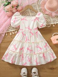 Elladie kids Đầm kiểu bánh kem 3D dễ thương cho bé gái, đầm đồng phục học sinh, thân đầm màu be nhạt, in họa tiết nơ hồng, cổ vuông, tay ngắn phồng, nơ hồng lớn trang trí ngực, viền bèo nhiều lớp, ngọt ngào và đáng yêu, toát lên vẻ ngây thơ của trẻ nhỏ. - Nhiều màu - Xem 2