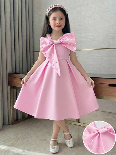 Young Girls' Elegant Socialite Style Pink Sleeveless Dress. The Top Half Uses Soft Fabric With A Large Bow Decoration And Faux Pearl Accents To Enhance The Visual Effect. The One Shoulder Strap Design Exposes The Delicate Shoulder And Neck Lines. The Waist Is Naturally Cinched To Accentuate The Figure. The Bottom Half Is A Fluffy A-Line Silhouette With A Flowing, Graceful Drape. The Overall Design Is A Sweet Princess Style. The Lightweight, Skin-Friendly Fabric Is Suitable For Birthday Parties, Piano Recitals, Flower Girl Ceremonies, Formal Events, And Other Occasions. One-Piece Dress, Spring/Summer.