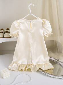 这款柔和米色的女婴连衣裙采用经典的圆领设计，搭配可爱的泡泡袖和精致的荷叶边袖口和下摆，并点缀着甜美的花朵图案，打造出可爱又简约的造型。旨在让您的宝贝像阿拉伯公主一样闪耀，是宴会、派对和其他特殊场合的完美之选。 - 杏色 - 查看 2