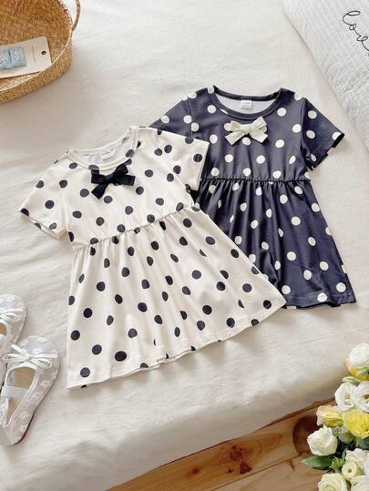 这款女童黑色杏色撞色圆领短袖A字波点连衣裙两件套，简约优雅，甜美复古，充满校园风情。针织面料，厚度适中，宽松版型，领口饰有蝴蝶结织带，波点印花图案更添复古甜美气息。适合日常出行、学校学习、生日派对、儿童节等各种庆祝活动。