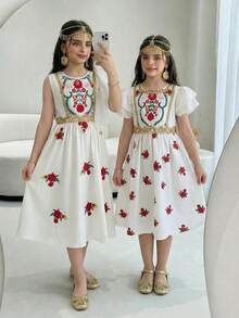 Sparklyn 少女春夏新款连衣裙，白色梭织面料，红色花卉数码印花图案，正面设计，精致金色滚边，白色双层荷叶边下摆，无袖圆领收腰连衣裙，适合少女穿着，简约优雅，精致甜美，适合日常、上学、外出、度假、派对、节日、新年等场合。另有其他款式，例如：小女孩墨西哥连衣裙、儿童连衣裙、女童亲子装、儿童夏季连衣裙、母女亲子装等。 - 白色 - 查看 4