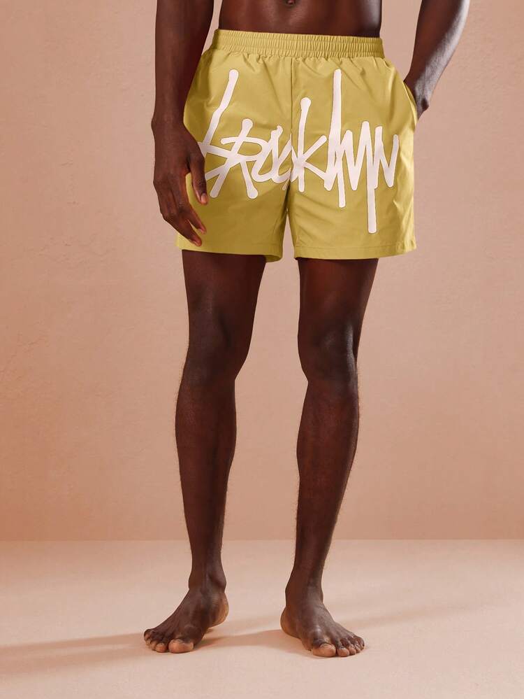 Short de bain d'été pour hommes avec imprimé graphique jaune moutarde et logo en script. Maillot de bain pour la piscine et les vacances