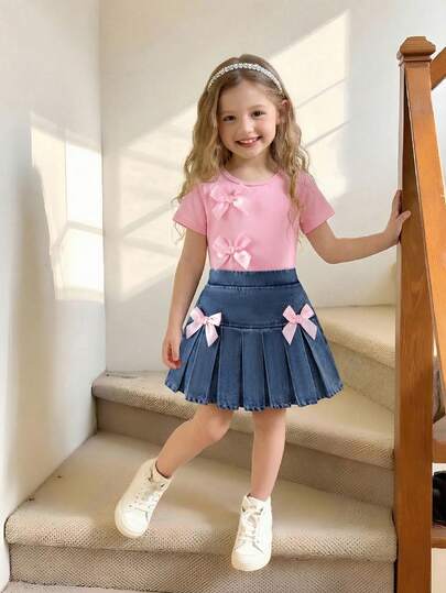 SHEIN סט של 2 יחידות לפעוטות בנות בסגנון בית ספר אופנתי ומתוק עם קישוטי סרט ופפיון ורודים עם שרוולים קצרים וחצאית ג'ינס עם קפלים, סט חולצת טי קיץ נוחה ופשוטה