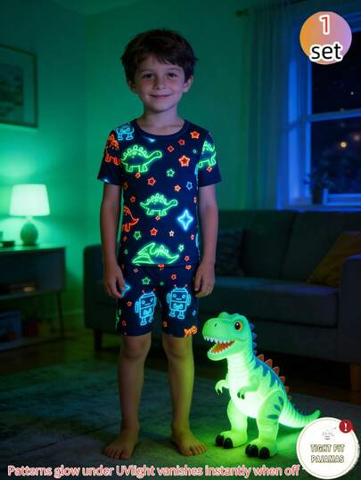 Bộ đồ ngủ cho bé trai, gồm áo thun ngắn tay cổ tròn màu xanh hải quân phát sáng trong bóng tối, họa tiết ngôi sao nhiều màu sắc, khủng long xanh lá cây và hình khối màu xanh nhạt, quần short cùng màu, chất liệu vải dệt kim mềm mại và thoải mái, thích hợp mặc trong nhà và ngoài trời vào mùa hè.
