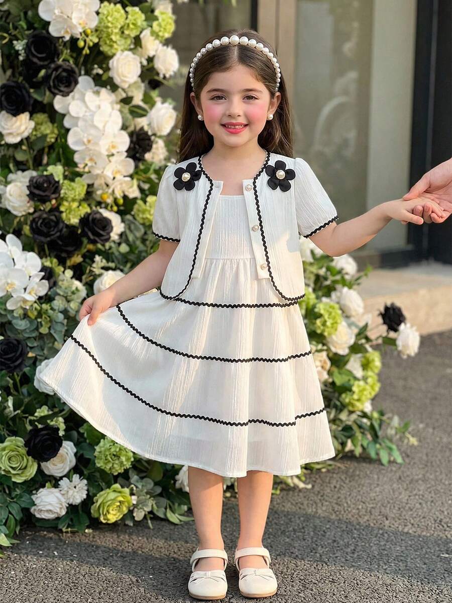 SHEIN Bộ váy hai dây màu trắng kem kiểu Pháp cổ điển dành cho bé gái, gồm váy và áo khoác cardigan tay ngắn. Váy được làm từ vải kẻ sọc dọc mềm mại, có phần gấu váy xếp tầng với viền lượn sóng màu đen. Áo khoác cardigan có cổ tròn được trang trí bằng họa tiết hoa 3D màu đen và viền lượn sóng đen. Thiết kế tổng thể tươi mới, tinh nghịch với chút ngọt ngào cổ điển. Váy nhẹ và áo khoác cardigan mỏng phù hợp cho những buổi đi chơi thường ngày, dạo chơi công viên hoặc những buổi họp mặt gia đình vào mùa hè. - trắng - Xem 1