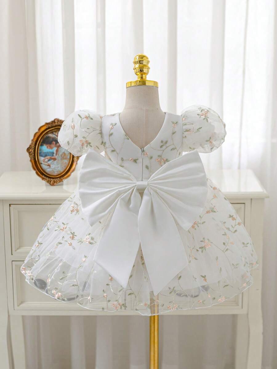 Glamorique Kids 这款女宝宝公主白色圆领修身A字长裙，饰有精美的花朵刺绣和大蝴蝶结，适合特别场合，如花童、生日派对、婚礼等。这款女宝宝公主裙，花朵刺绣，后背大蝴蝶结，蓬蓬裙摆，可爱可爱，适合派对或特殊场合拍照，让宝宝看起来更加自然美丽。四季皆宜，尽显女宝宝公主风范。