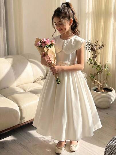 Bộ váy hai mảnh màu trắng dành cho bé gái tuổi teen, thiết kế cổ áo cách điệu. Váy có cổ áo lớn với cúc trang trí và viền ren. Kèm theo thắt lưng ren, phù hợp cho các buổi đi chơi, tiệc tùng và tháng Ramadan. Đây là một bộ váy thanh lịch theo phong cách cung đình. Bộ gồm hai mảnh.