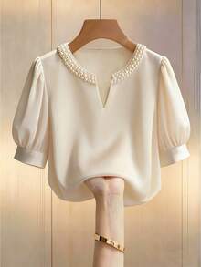 GlowEve 香槟色女士优雅圆领V领短袖休闲泡泡袖衬衫，饰以珍珠，宽松版型，适合通勤和日常穿着，尽显优雅气质。这款衬衫优雅休闲，适合女性日常穿着，也适合浪漫约会、情人节、商务办公等场合，是时尚休闲通勤、商务办公、日常休闲以及都市教师职业装的理想之选。 - 杏色 - 查看 1