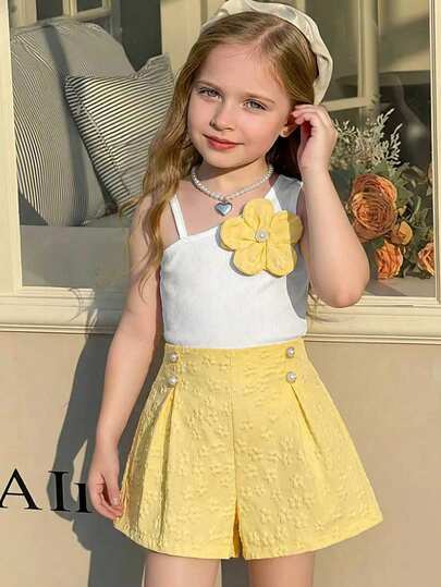两件套女童无袖碎花吊带背心和黄色短裤套装，春夏款。吊带背心采用窄肩带设计，正面饰有黄色碎花，清新甜美。黄色短裤采用提花面料，点缀珍珠和蓝色抽绳，精致俏皮。整体风格甜美可爱，适合女孩日常穿着和居家穿着。