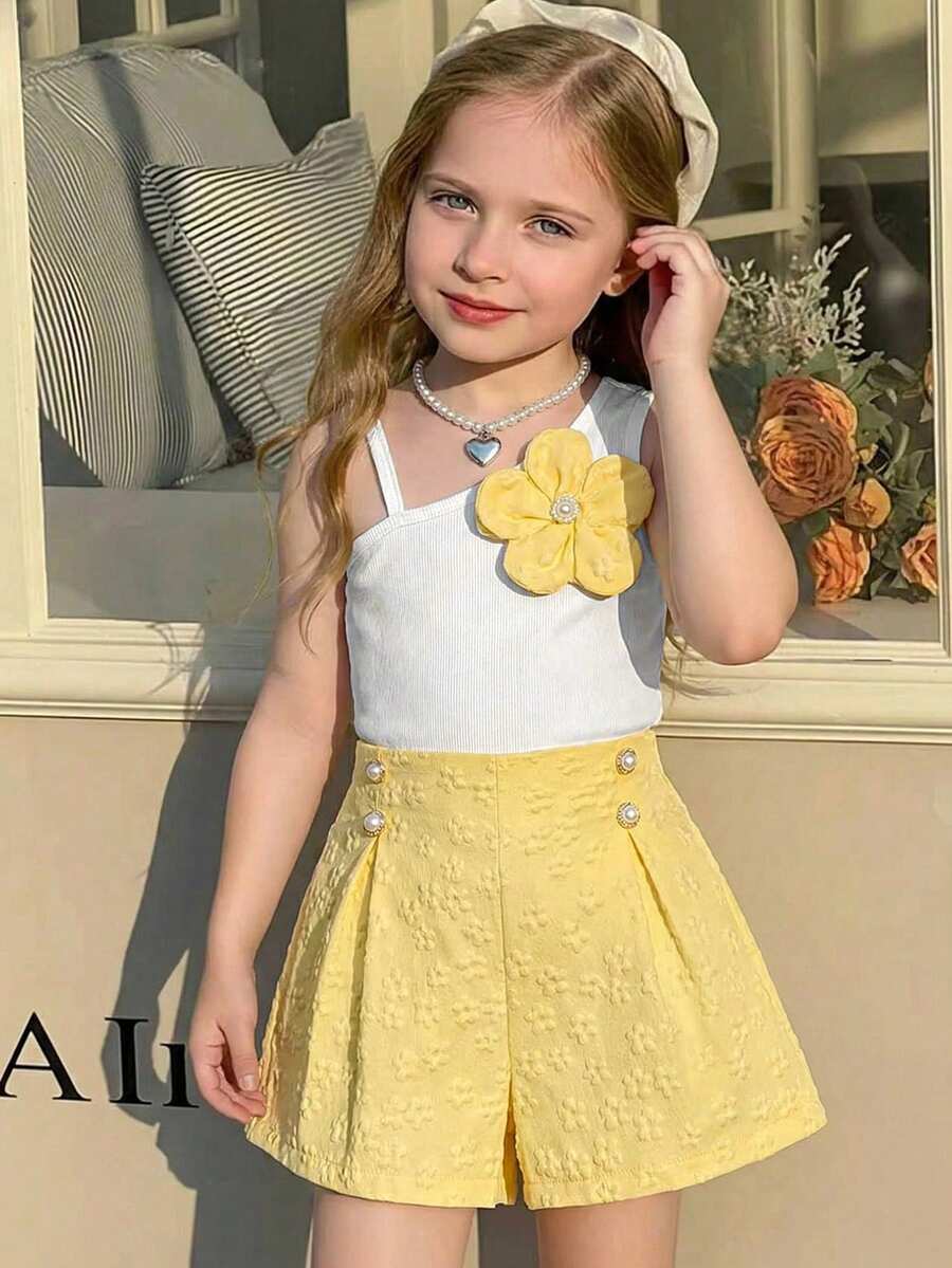 Elladie kids 两件套女童无袖碎花吊带背心和黄色短裤套装，春夏款。吊带背心采用窄肩带设计，正面饰有黄色碎花，清新甜美。黄色短裤采用提花面料，点缀珍珠和蓝色抽绳，精致俏皮。整体风格甜美可爱，适合女孩日常穿着和居家穿着。