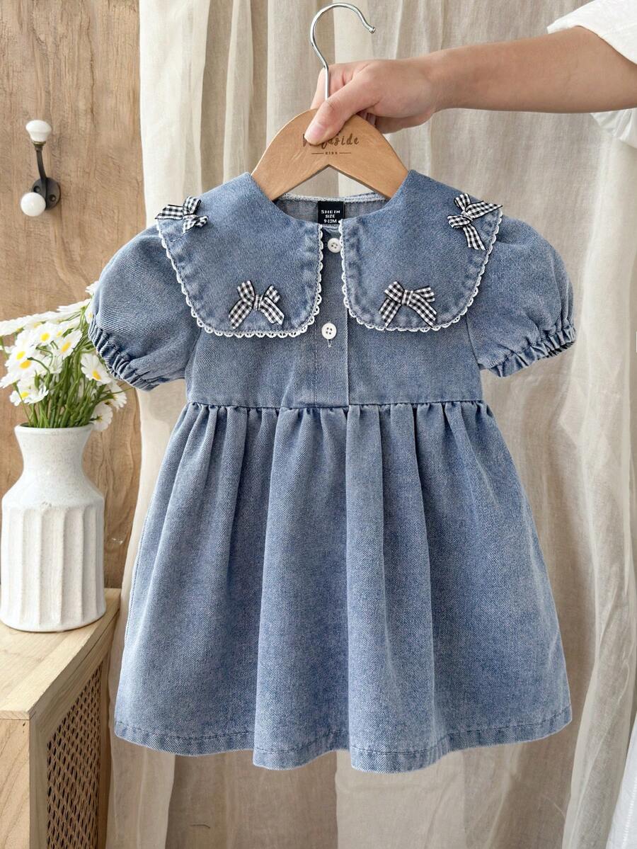 SHEIN Vintaside Kids 女婴牛仔休闲宽松短袖连衣裙，采用水洗做旧工艺，宽领设计，饰有可爱蝴蝶结，轻盈柔软的棉质牛仔面料，时尚百搭，是女孩们的必备单品，适合春夏穿着，休闲、拍照、外出、派对等场合皆宜，夏季新品上市。