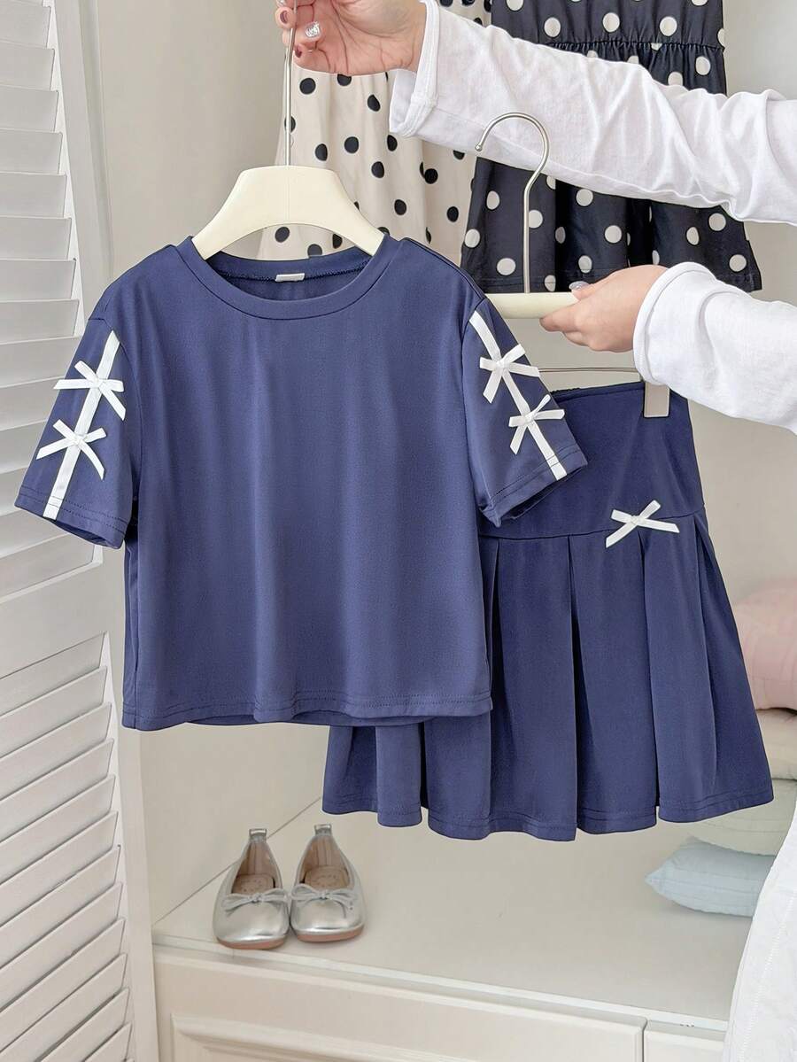 SHEIN Bộ đồ hai mảnh màu xanh navy mùa hè này gồm áo thun ngắn tay cổ tròn và chân váy xếp ly cạp cao, mang đến phong cách học đường thời trang, đơn giản, thoải mái và ngọt ngào. Được làm từ vải dệt kim, chất liệu có độ dày vừa phải và ôm sát cơ thể. Tay áo và thân váy được trang trí bằng nơ trắng, rất phù hợp cho trường học, các hoạt động ngoại khóa, thư giãn tại nhà và tham dự các bữa tiệc, v.v. - Màu xanh hải quân - Xem 1