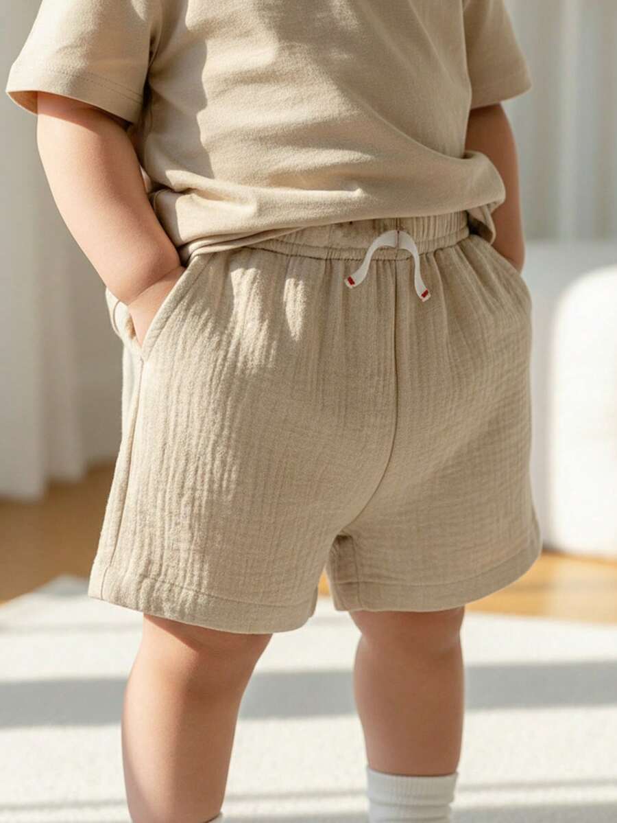 男婴休闲双层纱布短裤，带口袋和松紧腰带，装饰绳设计，百搭风格，适合日常穿着、上学、旅行、运动——婴儿/幼儿短裤、新生儿短裤、夏季婴儿短裤、婴儿裤、带口袋男婴短裤、男女通用短裤、婴儿度假短裤 - 卡其色 - 查看 1