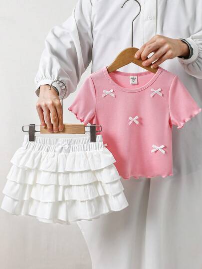 SHEIN Bộ đồ mùa hè cho bé gái, kiểu dáng thường ngày: áo hồng thắt nơ và quần short trắng xếp ly.