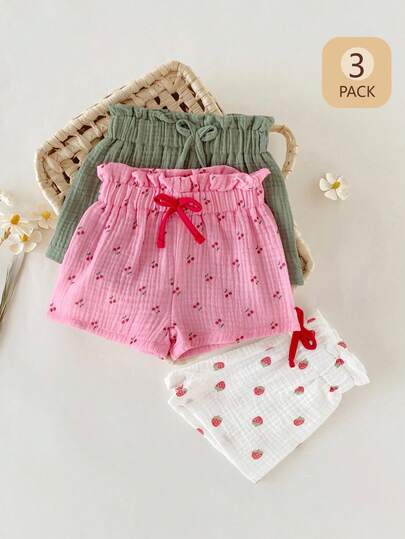 SHEIN Bộ 3 món quần short cho bé gái kiểu dáng thường ngày, in hình hoa dâu tây và anh đào, màu trắng, hồng, xanh lá cây, có bèo nhún và nơ ở eo, thoải mái và đa năng cho hoạt động ngoài trời hoặc mùa hè.
