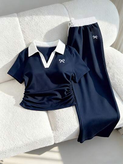 Conjunto deportivo casual para adolescentes, con cuello polo, costuras de contraste, bordado en el pecho, top de manga corta con pliegues en la cintura y pantalones anchos con cordón. Este conjunto deportivo azul marino equilibra perfectamente la comodidad y el estilo. Refinado pero no llamativo, los pantalones anchos con cintura ajustable y el cuello polo de contraste pueden resaltar la línea del cuello. Un atuendo esencial de verano para relajarse, hacer ejercicio o usar al aire libre.