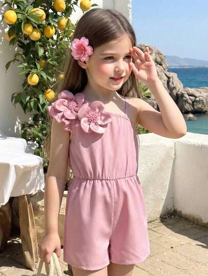女童无袖连体裤，不对称设计，一侧为短袖，另一侧为细肩带，宽松短裤，饰有花朵和珍珠，腰部隐形褶裥，柔和的粉色调，甜美公主风，适合日常穿着。