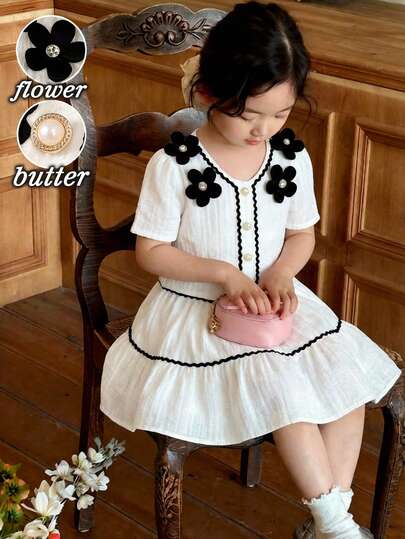 Elladie kids Unga flickor vår/sommar nytt svartvitt färgblocksskjortset. Vitt vävt vågigt tyg, vit diamantdekor framtill, svart 3D-blommig accent, svart vågig volangkant, vit metallpärlknappsslå med kortärmad skjorttopp i kombination med svart vågig volang, vit enfärgad A-linjekjol i 2-delat set. Sofistikerad, minimalistisk, elegant och damlik stil, lämplig för skolan, utflykter, semestrar, fester och högtider på vår/sommar. Flicka vintageklänning Flickaklänningar elegant casual småbarnsflicka krämfärgad och svart