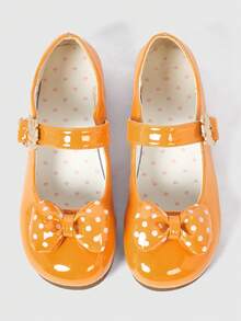 Orange shiny leather + polka dot bow.