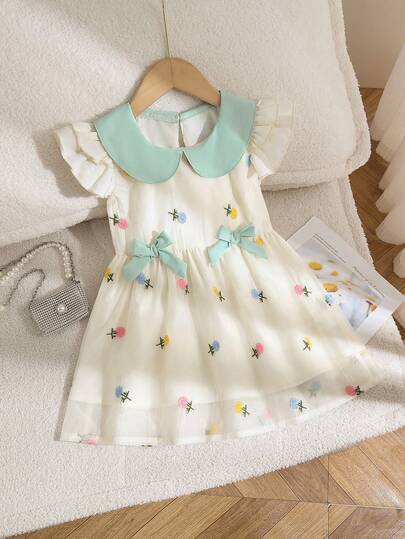 女童田园公主风连衣裙，春夏款，浅绿色大娃娃领，搭配短款泡泡袖，腰间饰有绿色蝴蝶结，色彩缤纷的刺绣花卉图案，A字廓形，面料柔软舒适，适合休闲度假和日常穿着。