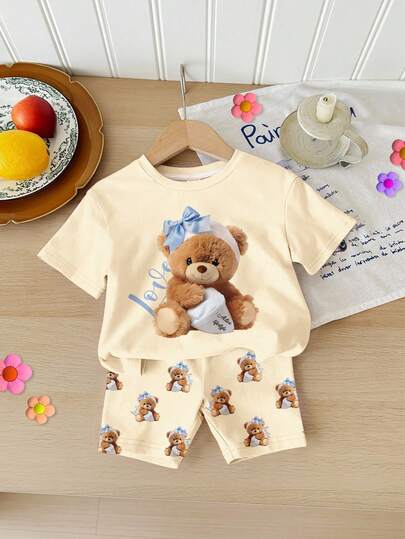 SHEIN Baby Girl Cream Yellow, Adorable Butter Bear Print, Casual Minimalist Soft Round Neck Loose Short Sleeve T-Shirt And Tight Cycling Shorts Set, Suitable For Spring/Summer Daily Wear, Street Style, Outing, Home, Vacation, Picnic, Farm