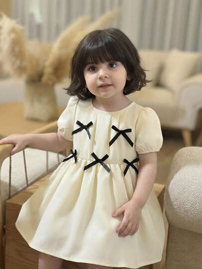 这款女婴纯色圆领泡泡袖A字连衣裙饰有3D蝴蝶结，精致可爱，A字廓形经典时尚，适合各种体型的宝宝。无论是日常外出、居家休闲还是参加派对，都能让您的宝宝成为最耀眼的小公主。它也是妈妈们为宝宝挑选的理想时尚单品。