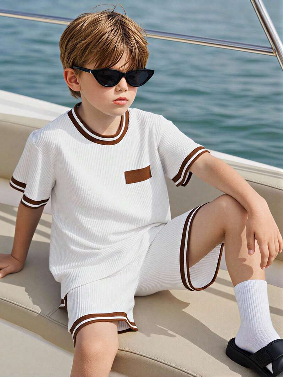 Bộ 2 món đồ thể thao thường ngày cho trẻ em, áo thun ngắn tay và quần short, màu be nhạt. Áo thun cổ tròn tay ngắn có viền sọc nâu ở cổ áo và cổ tay, cùng một miếng vá vuông màu nâu trên ngực. Quần short có viền sọc nâu ở gấu quần, kiểu dáng đơn giản nhưng năng động, phù hợp cho trẻ em mặc hàng ngày. - trắng - Xem 1
