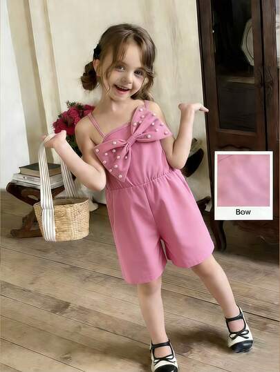 这款小女孩粉色连体裤采用细肩带设计，上身是无肩带款式，下身是褶皱短裤。胸前饰有大蝴蝶结，并点缀着电脑刺绣珠子。高腰设计非常适合春夏外出、海滩度假和生日派对。