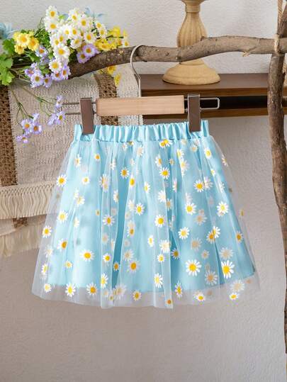 A Little Girl's Elegant Blue Skirt, Featuring A Layered Design With A Transparent Outer Layer Of Daisy-Printed Mesh Fabric. The Elastic Waistband Makes It Suitable For Everyday Wear, Beach Vacations, And Casual Outings