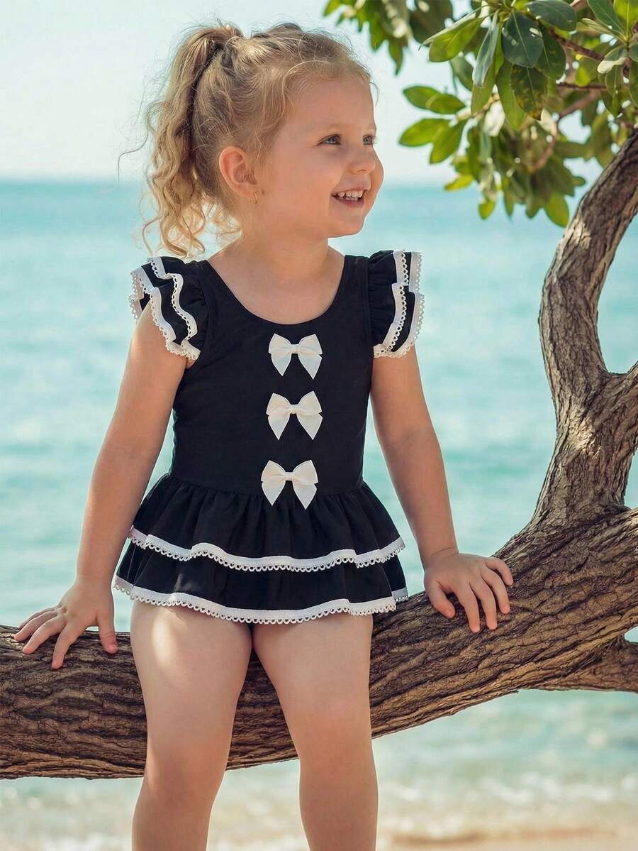 SHEIN Emery Rose Kids Young Girl Contrast Binding Ruffle Armhole Bow Front One-Piece Swimsuit, Summer Beach Vacation Style Girls Black And White Beach Outfit Young Girl Swimsuit Black And White Twin Girl Beach Clothes Black Bathing Suits For Girls Girls Black With White Bows Cute Young Girl And Baby Girls Black Ruffled Swimsuit With White Trim And Bows Sweet Beach Outfit - Black - View 1