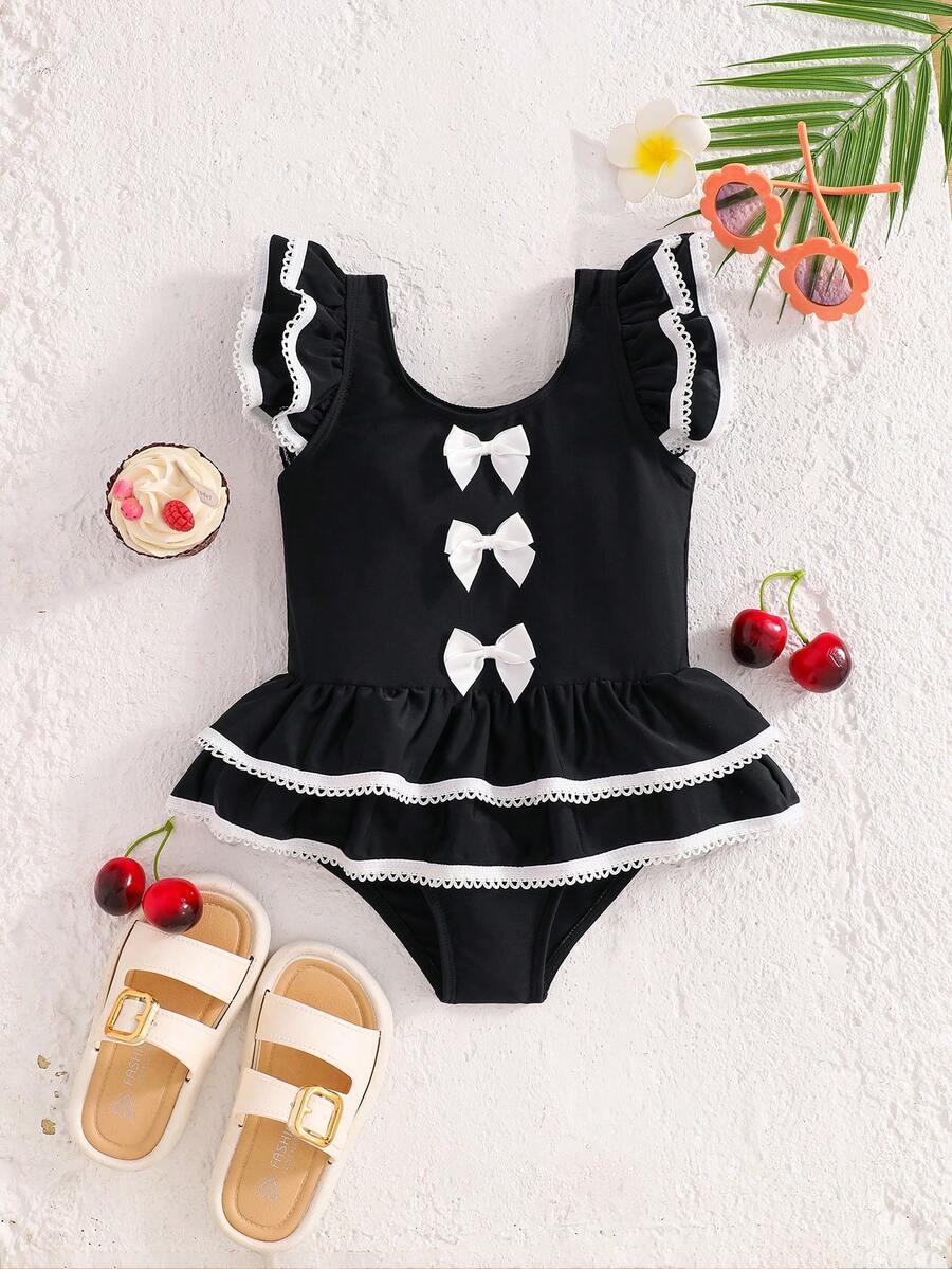 SHEIN Emery Rose Kids Bộ đồ bơi liền thân cho bé gái, viền tương phản, bèo nhún, tay áo và nơ phía trước, kiểu dáng nghỉ hè trên bãi biển, trang phục đi biển đen trắng cho bé gái, đồ bơi đen trắng cho bé gái, quần áo đi biển đen trắng cho bé gái sinh đôi, đồ bơi đen cho bé gái với nơ trắng, đồ bơi bèo nhún đen dễ thương với viền trắng và nơ, trang phục đi biển ngọt ngào đen trắng, bộ đồ bơi đồng bộ cho bé gái, bộ đồ bơi đen đồng bộ cho bé gái. - màu đen - Xem 1