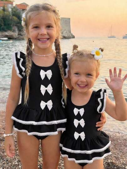 SHEIN Emery Rose Kids Young Girl Contrast Binding Ruffle Armhole Bow Front One-Piece Swimsuit, Summer Beach Vacation Style Girls Black And White Beach Outfit Young Girl Swimsuit Black And White Twin Girl Beach Clothes Black Bathing Suits For Girls Girls Black With White Bows Cute Young Girl And Baby Girls Black Ruffled Swimsuit With White Trim And Bows Sweet Beach Outfit