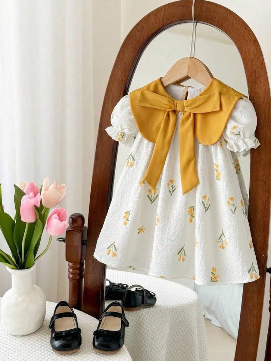 SHEIN LMoss Kids 女婴碎花蝴蝶结连衣裙，色彩缤纷的碎花图案，蝴蝶结领口，宽松优雅的款式，适合夏季穿着，充满乡村气息，轻盈透气，是户外活动、居家休闲聚会的理想之选。 - 杏色 - 查看 1