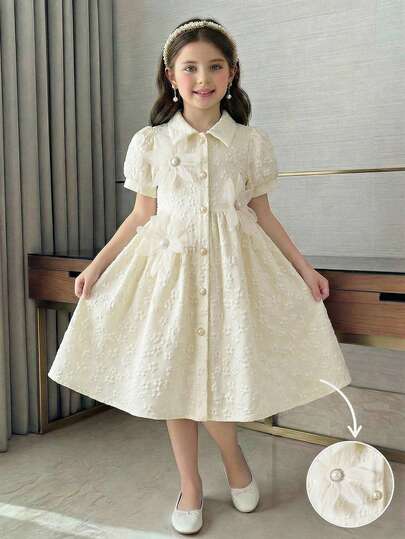 这款少女经典彼得潘领泡泡袖连衣裙延续了优雅童装的美学理念，蓬松的袖子设计凸显了优雅高贵的气质，尽显精致奢华。3D珍珠花朵装饰，多层雪纺花瓣层叠交错，中心点缀着一颗圆润的珍珠，散发着复古奢华的气息。象牙色提花面料，质地细腻光泽，低调而精致，适合宴会、庆典等正式场合，完美展现优雅高贵的小公主风范。