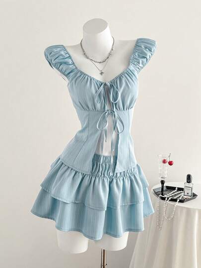 Elamini Phong cách retro ngọt ngào, gợi cảm, dễ thương, thích hợp cho kỳ nghỉ, đi học, hẹn hò, dạo phố. Bộ 2 món gồm áo tay ngắn thắt nơ cổ bẻ màu xanh trắng và chân váy mini xếp tầng dáng chữ A, eo chun, thích hợp cho mùa xuân/hè/thu.