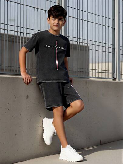 两件套夏季新款休闲青少年男童套装，包括一件做旧水洗黑色短袖T恤和一条印有加州字母图案的松紧腰短裤，宽松版型，适合日常、通勤、运动、街头穿搭和ins风。