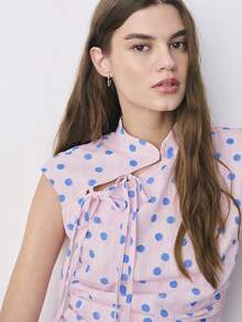 Nöista 这款无袖波点修身上衣采用立领设计，侧边系带，并饰有精致的褶皱，勾勒出优美的身形。轻盈的纹理面料散发着俏皮的魅力，是春季、春夏、休闲约会、复古造型以及从白天到夜晚各种场合的完美之选。 - 粉色 - 查看 5