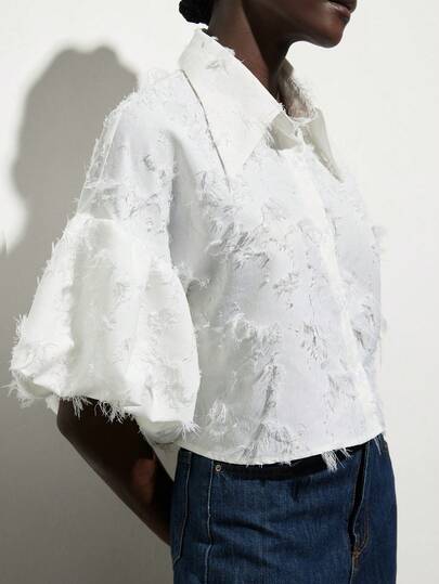 Aveloria Modichic White Collar Short Puff Sleeve Blouse, Unique Tassel Jacquard Texture Fabric, Minimalist Modern Style, Suitable For Spring/Summer Commute, Date, Picnic, Casual, Daily Wear, Loose Lantern Sleeve Design Element, Lightweight, Short Loose Fit, Soft Polyester Fabric. Key Fashion Keywords: Short Shirt, Wide Sleeve Design, European And American Bestseller, Versatile Casual, Fashionable Fresh, Comfortable Cool, Thin, Retro , Exquisite Details. Tassel Jacquard Fabric, Lantern Puff Sleeve Decor, Stylish Short Sleeve Blouse