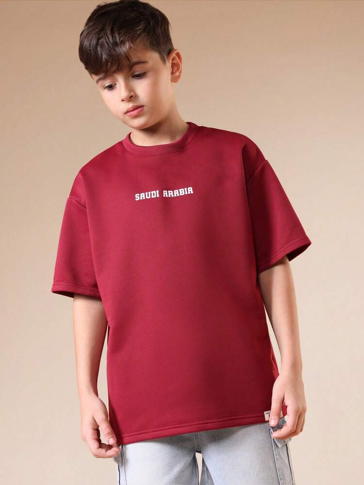 T-shirt graphique à col ras-du-cou à manches courtes de coupe régulière pour garçons, de couleur bordeaux, avec imprimé texte Arabie Saoudite, style décontracté