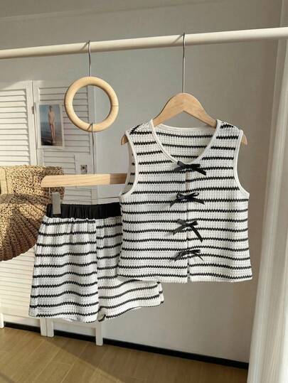 SHEIN Este conjunto de 2 piezas para niñas preadolescentes presenta un elegante y casual chaleco de cuello redondo de rayas jacquard negro y blanco inspirado en las vacaciones, emparejado con shorts a juego. La parte delantera está adornada con un lazo de cinta negra, creando un look sencillo, elegante y cómodo. Adecuado para actividades interiores y exteriores, deportes, fiestas escolares y otras ocasiones. Un conjunto de alta calidad para primavera/verano.