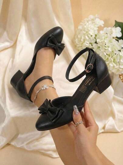 Zapato de tacón bajo con moño y pulsera al tobillo en color negro
