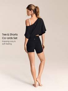GLOWMODE Bộ đồ thể thao gồm áo thun ngắn tay trễ vai mềm mại như lụa Tencel™ Modal và quần đùi biker cạp cao 10cm FeatherFit™ ôm bụng, không đường may, thích hợp cho các hoạt động như yoga, pilates, đạp xe, chạy bộ, tập gym và các hoạt động thể thao hàng ngày. - màu đen - Xem 2