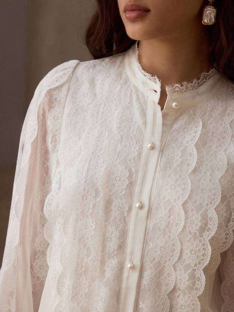 Chemise à col montant blanc en dentelle avec bordure festonnée et manches bouffantes