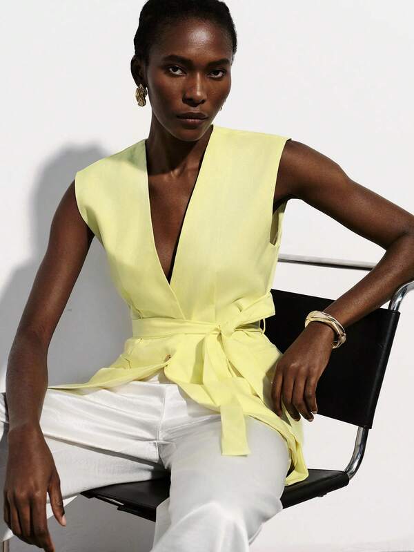 Aveloria Modichic Light Yellow Sleeveless Suit Vest, V-Neck Design, Tie Waist, Metal Button Detail, Tailored Underarm, Slim Fit, Smooth Fabric, Minimalist Modern Style, Suitable For Work, Business Meetings, Leisure, Spring/Summer, Emphasizing Capable And Elegant, Pair With Pants Or Skirts To Enhance Overall Chic And Sophistication. Commuter Delight Vest With Waist Tie And Fake Pockets, V-Neck Ladies Top