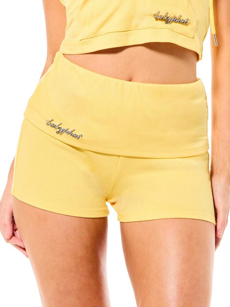 BABYPHAT Short femme taille haute avec taille pliante côtelée, détail de texte avec strass. Short d'été casual ajusté et stretch, couleur jaune