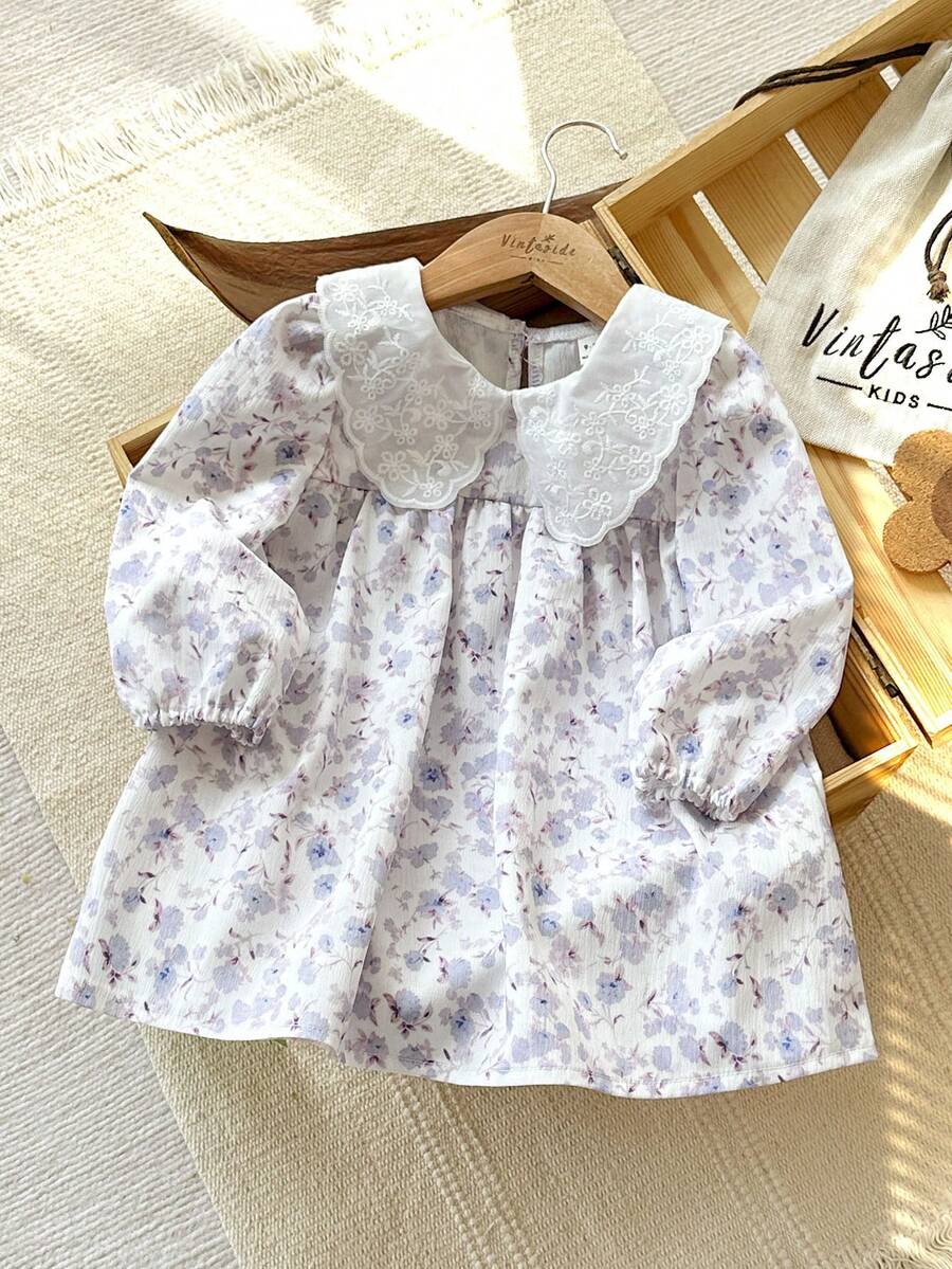 SHEIN Vintaside Kids 这款春秋季女宝宝多色娃娃蕾丝领长袖A字连衣裙，活泼优雅，飘逸灵动，展现出清新甜美的乡村淑女风范。连衣裙通体印有柔美的花卉图案，面料厚度适中。领口和下摆饰以精致蕾丝，散发着复古时尚气息。适合上学、花丛漫步、周岁生日庆祝以及参加婚礼等场合。