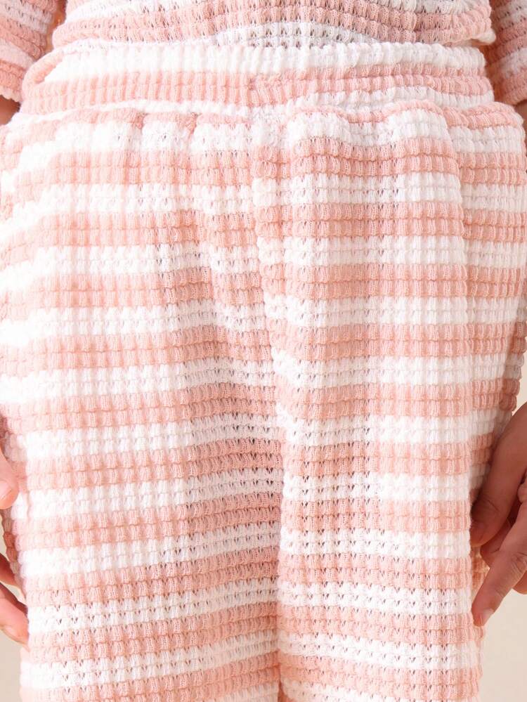 Koszulka polo i spodenki szydełkowe w pasującym komplecie z kołnierzykiem, krótkimi rękawami i poziomym wzorem w paski. Letni, swobodny strój.