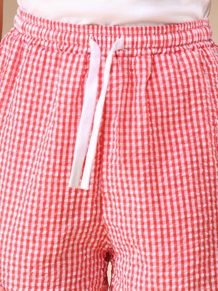 Set coordinato per ragazze pre-adolescenti, composto da t-shirt con stampa cupcake e pantaloncini a quadri bianchi e neri con dettagli in pompon bianchi, outfit casual per l'estate